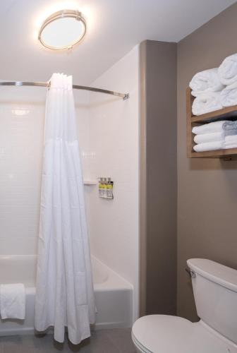 a bathroom with a white shower curtain and a toilet at Staybridge Suites - Lake Jackson by IHG in Lake Jackson