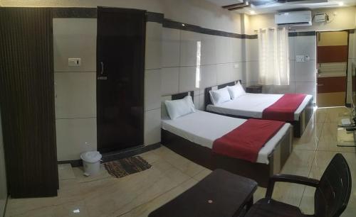 a hotel room with two beds and a chair at Sar Raj S R RESIDENCY in Vellore