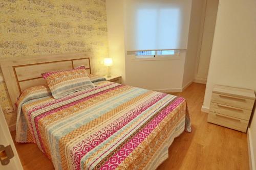 a bedroom with a bed with a colorful blanket and a window at Poeta 1 Bedroom Apartment IHAEP11119 in Fuengirola