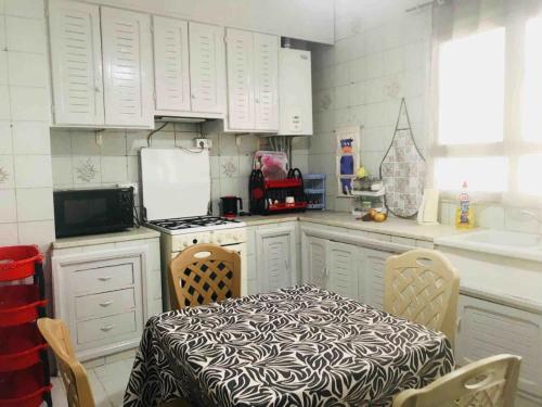 a kitchen with white cabinets and a table and chairs at Appartement Manzah 6 in Ariana