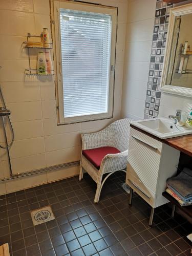 a bathroom with a sink and a chair with a window at Kouvola Guest house in Kouvola