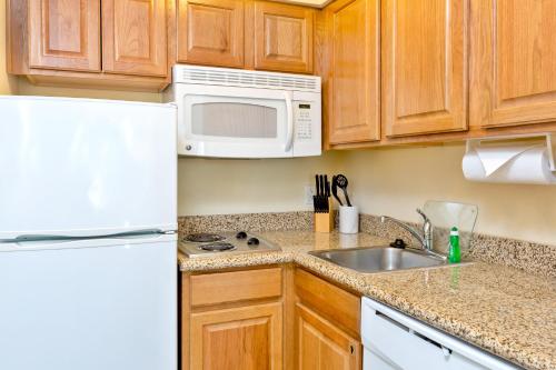 a kitchen with a white refrigerator and a sink at Staybridge Suites McAllen by IHG in McAllen