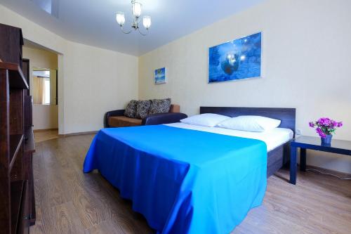 a bedroom with a blue bed and a couch at OK! Советская, 69 №9 in Tomsk