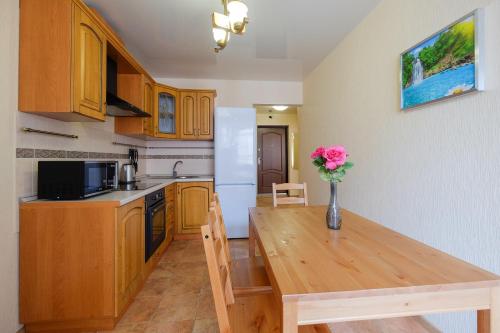 a kitchen with a wooden table and a vase of flowers at OK! Советская, 69 №9 in Tomsk