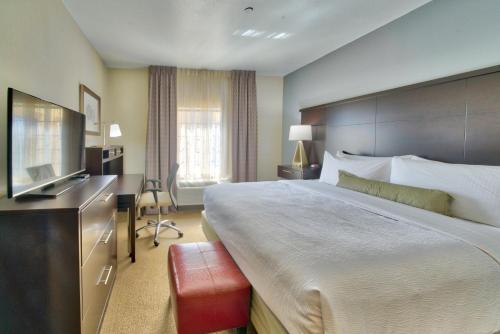 a hotel room with a large bed and a television at Staybridge Suites Lubbock South by IHG in Lubbock