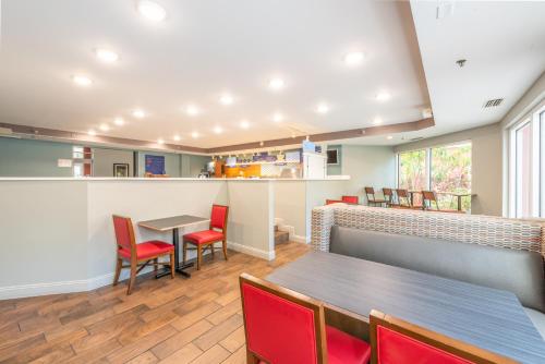 a restaurant with red chairs and a table and a counter at Holiday Inn Express Hotel & Suites Bradenton West by IHG in Bradenton