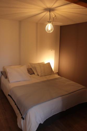 - une chambre avec un grand lit blanc et une lumière dans l'établissement Au calme face au grand paysage, à Essert-Romand