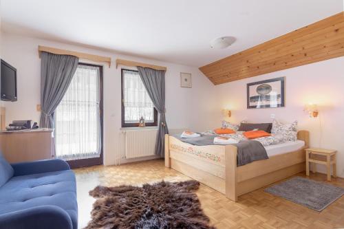 1 dormitorio con 1 cama y 1 sofá azul en Apartments Ukanc, en Bohinj