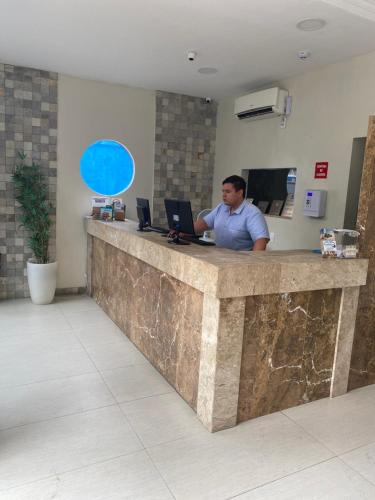 a man sitting at a counter with a laptop at Hotel Aquarius in Fortaleza