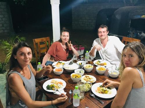 a group of people sitting around a table eating food at Bindu Homestay in Wellawaya