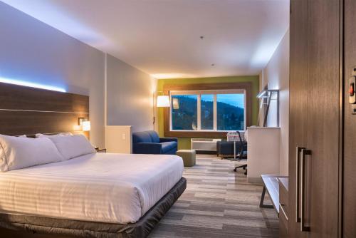 a hotel room with a bed and a living room at Holiday Inn Express & Suites Victoria-Colwood by IHG in Victoria