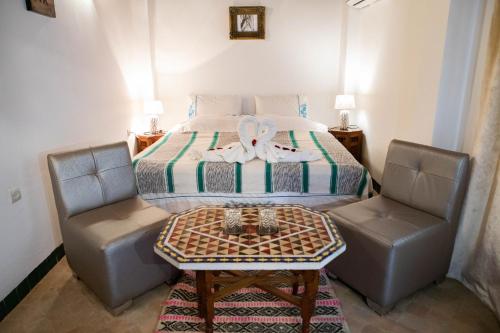 a bedroom with a bed with two chairs and a table at Dar Settash in Fès