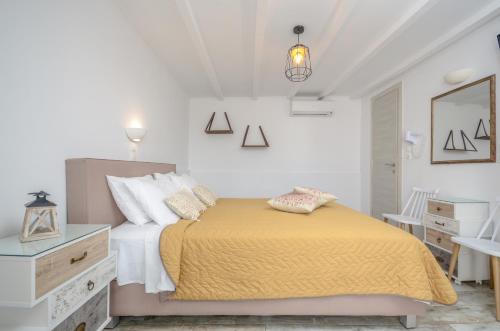 a white bedroom with a bed and a dresser at Saint George Hotel in Naxos Chora