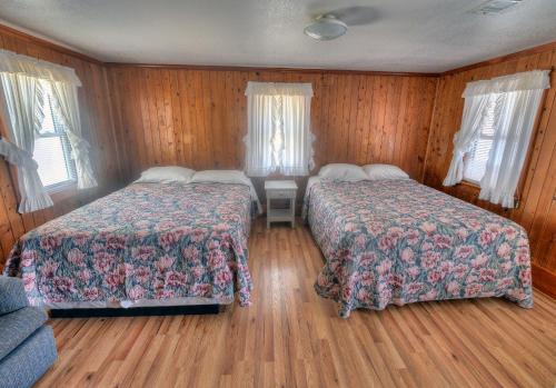 two beds in a room with wooden walls and wood floors at Outer Banks Motel in Buxton