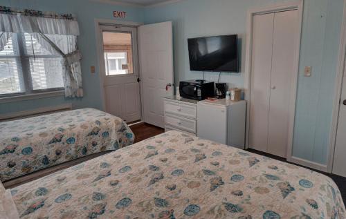 a bedroom with two beds and a flat screen tv at Outer Banks Motel in Buxton