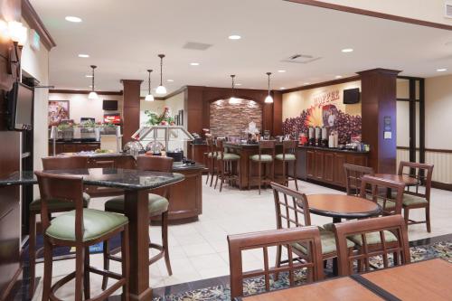 un ristorante con tavoli e sedie e un bar di Staybridge Suites Lafayette-Airport by IHG a Lafayette