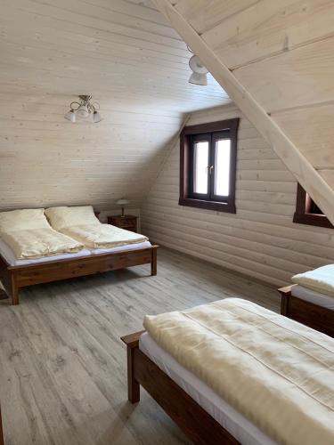 a attic room with two beds and a window at Roháčske zruby 2,3,4 in Zuberec