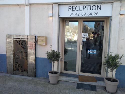 Hotel renaissance martigues في مارتيغ: يوجد متجر به اثنين من النباتات الفخارية أمام الباب