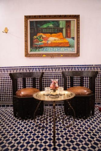a room with two chairs and a table and a painting at Dar Settash in Fès