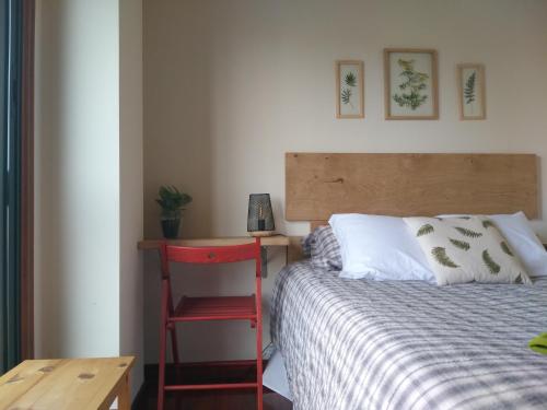 sypialnia z łóżkiem z czerwonym krzesłem obok biurka w obiekcie Apartamento completo con parking privado y WiFi en San Roque w mieście Vigo