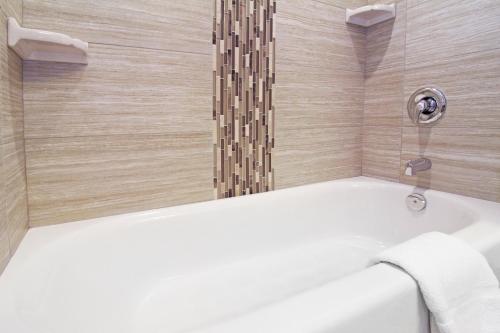 a bathroom with a bath tub with a shower at Holiday Inn Express and Suites Calgary University by IHG in Calgary
