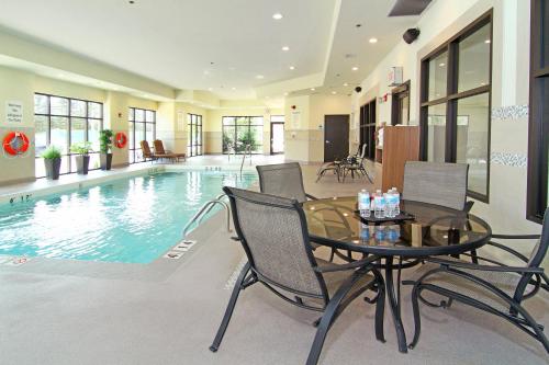 a pool with a table and chairs next to a pool at Holiday Inn Express and Suites Calgary University, an IHG Hotel in Calgary