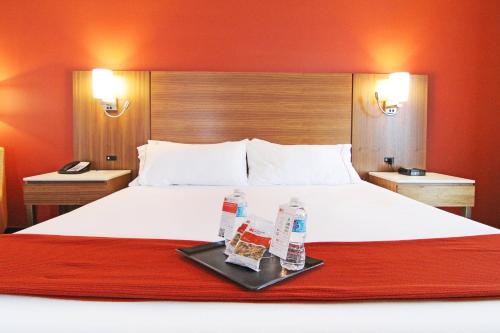 a hotel room with a bed with two water bottles on a tray at Holiday Inn Express and Suites Calgary University by IHG in Calgary