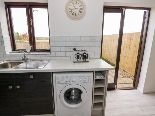 a kitchen with a washing machine and a sink at Kite Cottage in Brackley