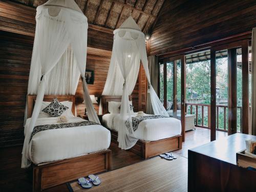 Bale Gede Lembongan في نوسا ليمبونغان: سريرين مع ناموسية في غرفة مع نوافذ