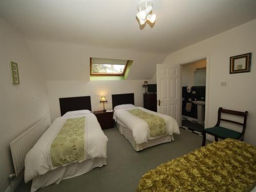 a hotel room with two beds and a chair at Launard House in Kilkenny
