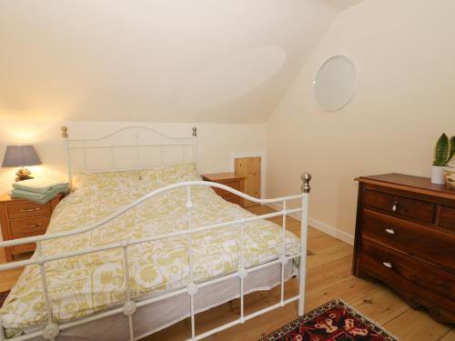 a bedroom with a white bed and a wooden dresser at Pipistrelle Cottage in Great Driffield