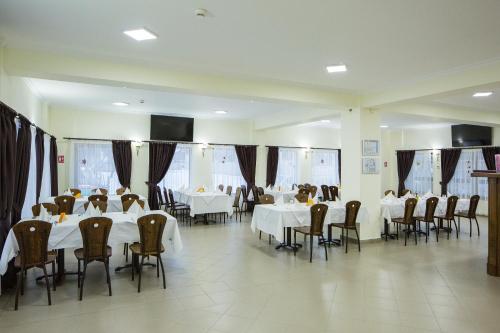 uma sala de jantar com mesas e cadeiras brancas em Hotel Rabbit Bran em Moieciu de Jos