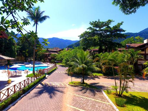 a resort with a pool and palm trees and mountains at Maresias Canto do Mar in Maresias