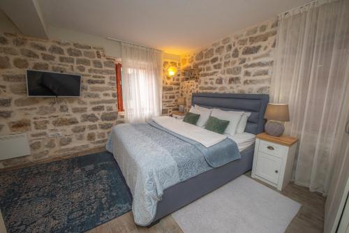 a bedroom with a bed with a stone wall at Antika Guesthouse in Kotor