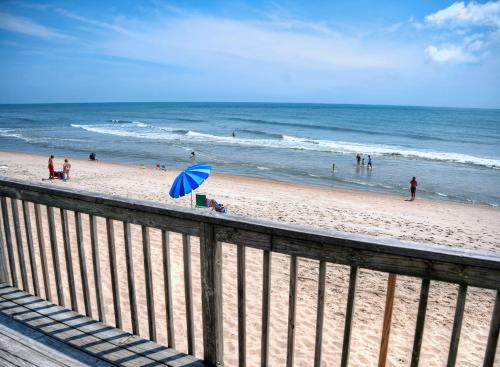 a beach with a blue umbrella and people on the beach at Outer Banks Motel in Buxton