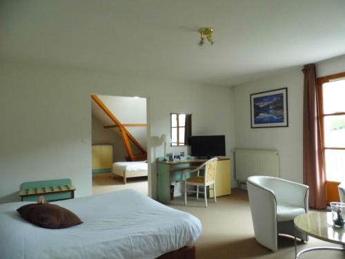 a bedroom with a bed and a desk and a table at Hôtel les Bergeronnettes in Champagneux