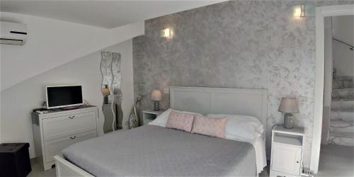 a bedroom with a white bed and a television at La Petite Maison in Taormina