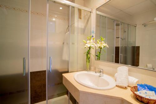 a bathroom with a sink, mirror, and bath tub at Hotel Amoros in Cala Ratjada