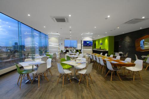 una sala da pranzo con tavoli, sedie e finestre di Holiday Inn Express & Suites Puebla Angelopolis, an IHG Hotel a Puebla