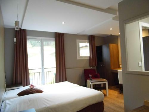 a hotel room with a bed and a window at Hôtel les Bergeronnettes in Champagneux