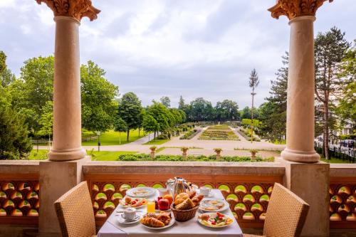 a table with food on a balcony with a view of a park at Pytloun Schlosshotel Weikersdorf in Baden