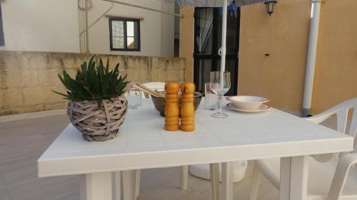 a white table with a plant and a vase on it at Mamina's House in il-Baħrija