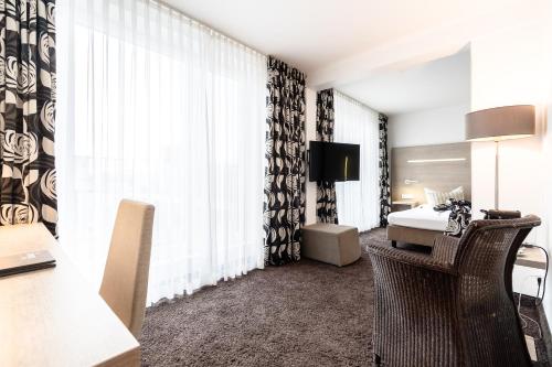 a hotel room with a bed and a desk with a chair at Hotel Demas City in Munich