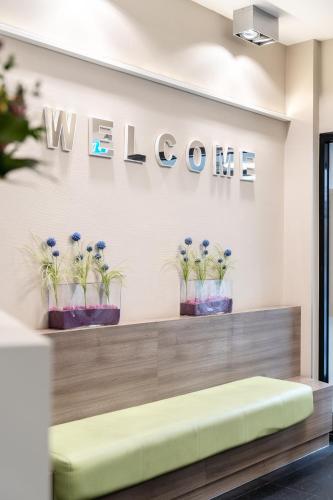 a lobby with a welcome sign and potted plants at Hotel Demas City in Munich