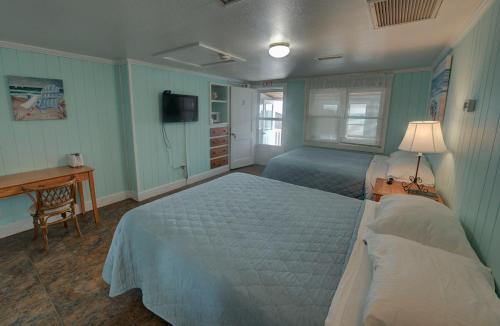 a bedroom with two beds and a desk and a television at Outer Banks Motel in Buxton