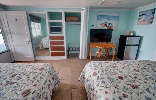 a bedroom with two beds and a desk and a television at Outer Banks Motel in Buxton