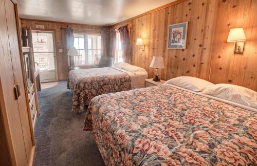 two beds in a hotel room with wooden walls at Outer Banks Motel in Buxton