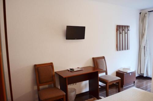 a room with a table and chairs and a tv on the wall at Vila Andrei in Băile Olăneşti