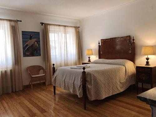 a bedroom with a large bed and two windows at Monte da Floresta B&B in Ferreira do Alentejo