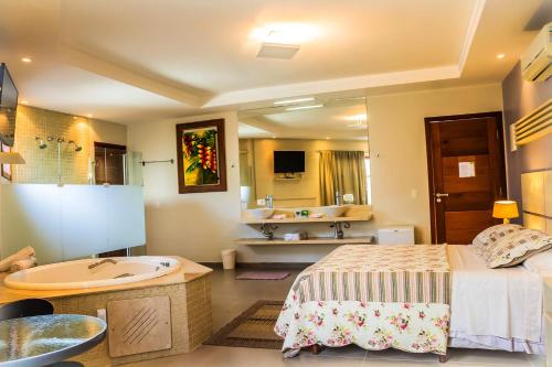 a bathroom with a bed and a tub and a sink at Pousada L'essence in Paraty